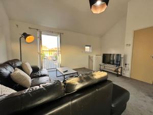 a living room with a leather couch and a television at Luxury home in rugby ready 4U 