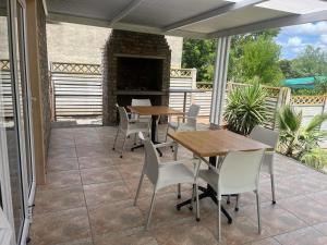 a patio with tables and chairs and a fireplace at Stay@51 Botha in Oudtshoorn