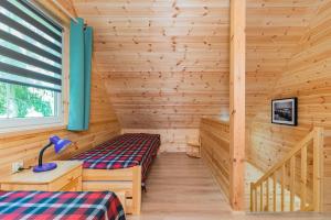 a log cabin with a bed and a window at Domek 7 osobowy piętrowy in Stegna