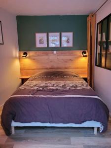 La maisonnette sous le cerisier في Bergonne: سرير مع اللوح الخشبي في غرفة النوم
