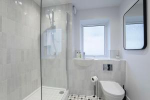 a bathroom with a shower and a toilet and a sink at Elliot Oliver - Exquisite Two Bedroom Apartment With Garden, Parking & EV Charger in Cheltenham