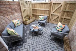 a patio with two chairs and a table with pillows at Elliot Oliver - Exquisite Two Bedroom Apartment With Garden, Parking & EV Charger in Cheltenham