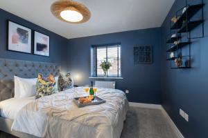 a blue bedroom with a bed with a tray of fruit on it at Elliot Oliver - Exquisite Two Bedroom Apartment With Garden, Parking & EV Charger in Cheltenham