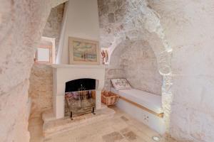 a living room with a fireplace in a stone wall at Villa Del Capitolo Con Trullo By Raro Villas in Carovigno