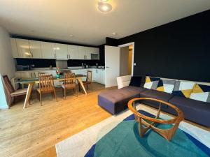 a living room with a couch and a table and a kitchen at Riverside Retreat with Spectacular Views Glasgow in Glasgow