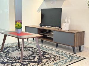 - un salon avec une télévision et une table dans l'établissement Desaru Cozy NetFlix WiFi 24LV9 By De Home, à Bandar Penawar