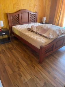 a bed in a room with a wooden floor at Cabaña Individual con piscina en parcela de Quillón in Quillón