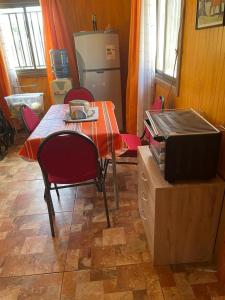 a kitchen with a table and chairs and a refrigerator at Cabaña Individual con piscina en parcela de Quillón in Quillón