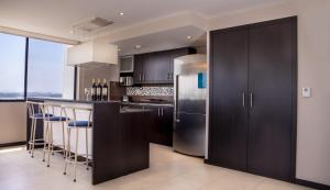 eine Küche mit schwarzen Schränken und einem Kühlschrank aus Edelstahl in der Unterkunft Suite 7 Bellini IV, Puerto Santa Ana, Guayaquil in Guayaquil