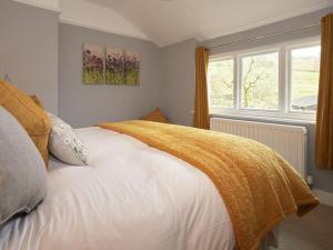 a bedroom with a white bed with a yellow blanket on it at 2 Bed in Borrowdale SZ068 in Rosthwaite