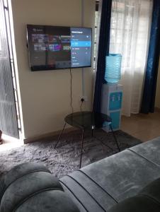 ein Wohnzimmer mit einem TV und einem Glastisch in der Unterkunft Bomet studio/bedsitter next to Chelsa Academy in Bomet