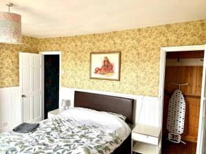 a bedroom with a bed and a painting on the wall at Inviting 4-Bed House near Heathrow with fireplace in Egham