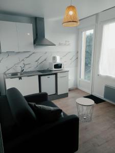 een woonkamer met een bank en een keuken bij O'ZEN - studio calme et lumineux avec jardin in Sablé-sur-Sarthe