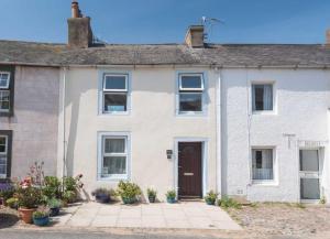 a white brick house with a brown door at 2 Bed in Ravenglass SZ409 in Ravenglass