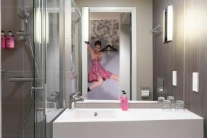 une femme sur une photo d'elle-même dans un miroir de bain dans l'établissement Moxy Edinburgh Airport, à Ingliston