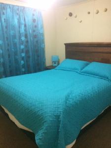 een slaapkamer met een bed met een blauw dekbed bij Arriendo casa Pucón in Pucón