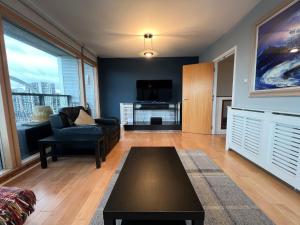 a living room with a couch and a tv at Duplex Apartment next to Hydro with Parking in Glasgow