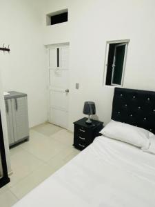 Un dormitorio blanco con una cama y una lámpara en una mesa. en Alojamientos Z.V, en Tumaco