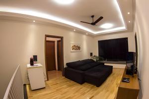 a living room with a black couch and a flat screen tv at Casa ampla e confortável próxima ao Santuário in Aparecida