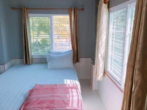 a bedroom with a bed and two windows at Chuttong resort in Trat