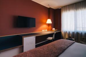 a hotel room with a bed and a desk with a tv at El Sant Cugat in Sant Cugat del Vallès