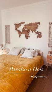 a bedroom with a bed with a wooden map on the wall at Paraíso a Dois em Estremoz in Estremoz