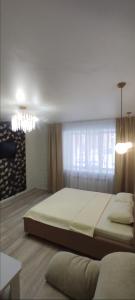 Un dormitorio con una cama grande y una lámpara de araña. en 1-комнатная квартира мкр. Аэропорт, en Kostanái