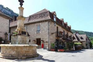an old building with a fountain in the middle of a street at Les appart'hotels de la fontaine in Autoire