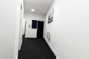 - un couloir avec des murs blancs et de la moquette noire dans l'établissement Ledger Loft, à Brierley Hill