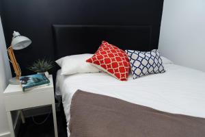 una cama con almohadas junto a una mesa en Ledger Loft, en Brierley Hill