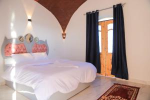 een slaapkamer met een wit bed en een raam bij Calm moon nights hostel in Al Aqālitah