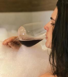a woman drinking a glass of wine in a bathtub at Chalés Vani in Resende +26 photos