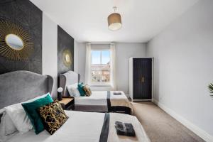 a bedroom with two beds and a mirror on the wall at Pristine Stylish Townhouse on the Stray - Sleeps 8 in Harrogate