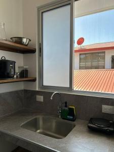 encimera de cocina con fregadero y ventana en Casa Abundia - Caracoles Studio, en Carrillo
