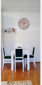 einen Tisch und Stühle mit einer Uhr an der Wand in der Unterkunft Andrea in Banja Luka