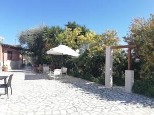 um pátio com um guarda-sol, mesas e cadeiras em B&B Borgo Degli Ulivi em Vieste