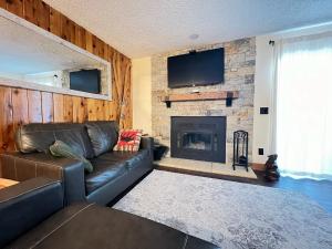 a living room with a leather couch and a fireplace at Silverado II in Winter Park
