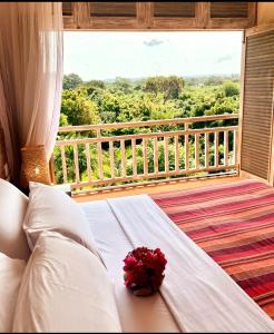 a bed in a room with a view of a balcony at Tombo House in Diani Beach