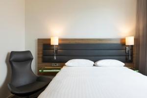 a bedroom with a bed and a black chair at Moxy London Excel in London