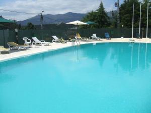 a large blue swimming pool with chairs and an umbrella at Hotel Boavista II in Melgaço