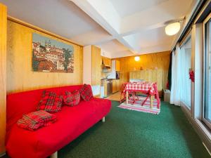 - un canapé rouge dans une chambre avec une table dans l'établissement Appartamento Cinzia Residence Solaria Marilleva 1400, à Mezzana