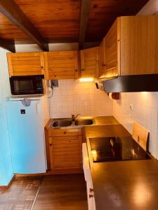 cocina con armarios de madera, fregadero y nevera en Chalet 10 couchages à 100m des pistes et commerces en Les Angles