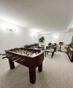 uma sala de estar com mesa de matraquilhos e sofás em ! 5 Bed Beautiful Home with Fenced Yard & Hammock! WEM - Foosball Table - WiFi - Fireplace - Long Stay em Edmonton