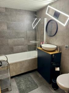 y baño con lavabo, bañera y espejo. en HappyLivingApartments, en Villach