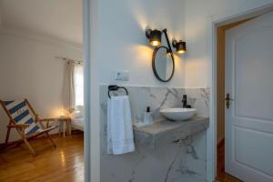 a bathroom with a sink and a mirror on a wall at Apartamento Aires - Trafaria in Trafaria