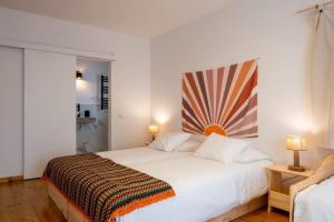 a bedroom with a white bed with a striped blanket on it at Apartamento Aires - Trafaria in Trafaria