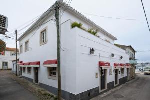 a white building with red awnings on a street at Apartamento Aires - Trafaria in Trafaria