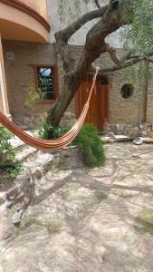 una hamaca colgando de un árbol delante de una casa en Residencia zona sierras chicas (casa) El talar en Mendiolaza
