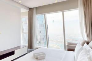 een slaapkamer met een wit bed en een groot raam bij Damac Heights - Locations in Dubai