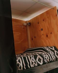 a small bed in a room with wooden walls at Alfar Hostel in Mar del Plata